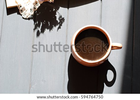 Cup of coffee, dry flowers with lace and open book on wooden table. Romantic, retro background; hard light
