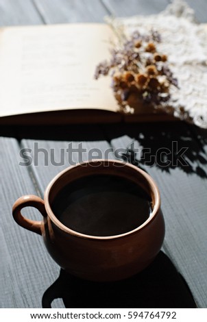 Cup of coffee, dry flowers with lace and open book on wooden table. Romantic, retro background; hard light