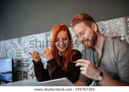 Close up portrait of a young couple enjoying working together from home on a digital tablet.