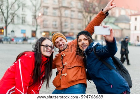 Three happy friends in a touristic city center, taking a self portrait  while visiting the city and having fun.