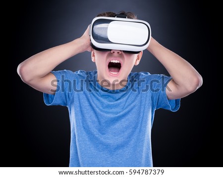 Amazed teen boy screaming, wearing virtual reality goggles watching movies or playing video games. Surprised teenager looking in VR glasses and shouting out loud. Child experiencing 3D gadget