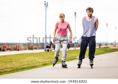 Outdoors activities sport and free time. Summertime exercising and healthy body. Young couple have fun together rollerblading in park.