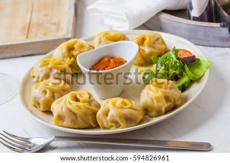 Nepalese traditional dumpling momos served with tomato chatni and fresh salad. Royalty-Free Stock Photo #594826961