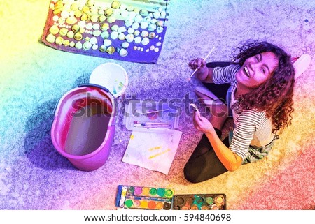 Brazilian girl painting shells on summer day. Top view at two kids sitting on patio floor painting with watercolors for creative family concept blog, toys business. Image with rainbow filter effect