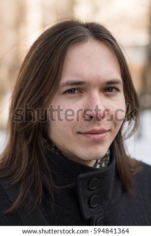 Handsome long hair brunette man wearing in black coat during cold winter day. In love. 