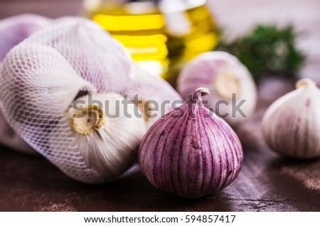 Raw whole garlic with oil and rosemary. Selective focus.