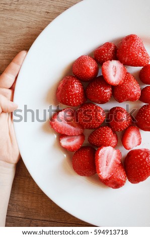 fresh ripe strawberries in a simple white bowl, on wood table