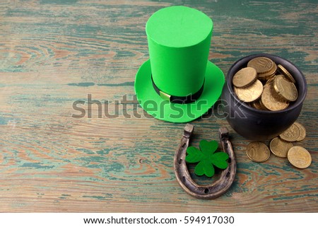 Happy St Patricks Day leprechaun hat with gold coins and lucky charms on vintage style green wood background. Top view