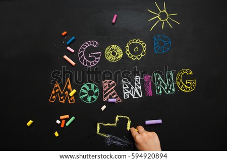 good morning. the kid draws on a black slate background. Good morning.