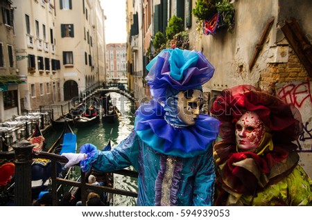 Two people in costumes on a bridge above the canal at carnival in Venice, Italy.