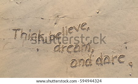 Handwriting words "Think believe dream and dare." on sand of beach
