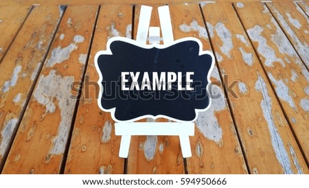 Business Concept - Chalk board with inscription EXAMPLE on a wooden table.  
