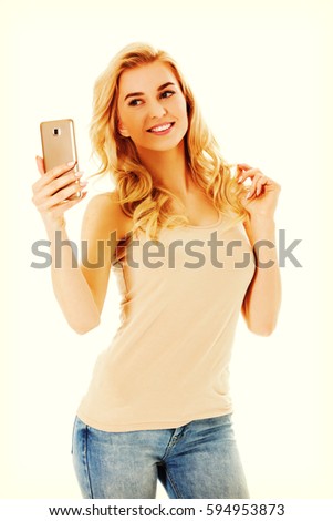 Happy young woman taking pictures of herself at smart phone