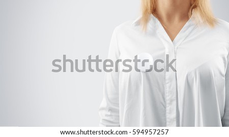 Blank button badge mockup pinned on the womans chest, close up view. Girl wear white shirt and campaign pin mock up. Volunteer round emblem design element. Pesron stand front view with voting symbol Royalty-Free Stock Photo #594957257
