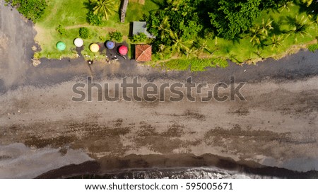 Top view on recreation area with umbrellas on the Keramas beach with black sand. Aerial view, Gianyar, Bali, Indonesia.