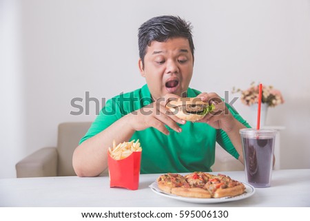 obese man having his lunch of junk or unhealthy food at home