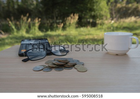 Business on financial report . Closeup coin and banknotes and Calculator , cup on wooden table.