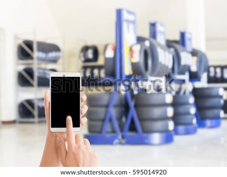 woman use mobile phone and blurred image of tires shop