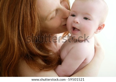 mother kissing little baby smiling on white background