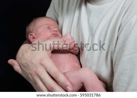 The father is holding a baby boy in his hands. He is trying to protect him. This is the baby's first photo shoot.