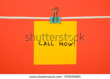 Yellow paper note on clothesline with text Call Now! over colorful background