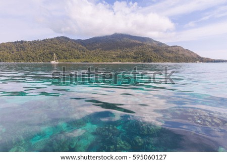 Beautiful seascape with yacht and coral reef and mountain under clouds background