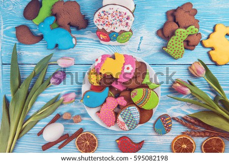 Tulips and gingerbread cookies on white and blue wooden background for Easter.
