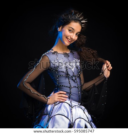 Portrait of a brunette girl in a dance suit posing on a black background in the studio