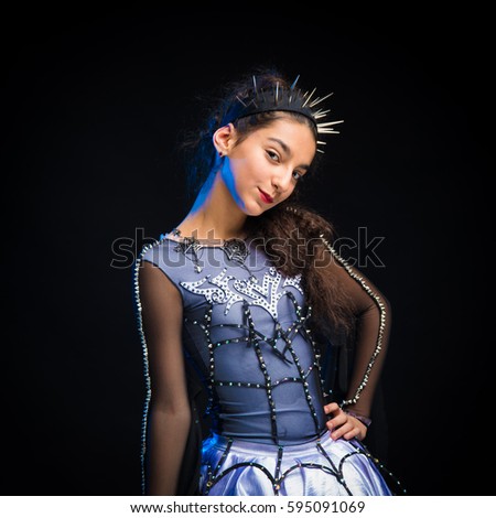 Portrait of a brunette girl in a dance suit posing on a black background in the studio