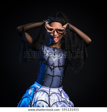 brunette girl in a dancing suit the queen spider posing on a black background in the studio