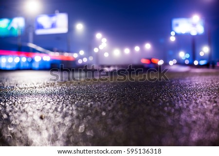 Foggy night in the big city, lantern lights on highway. Close up view from the asphalt level, image in the blue tones