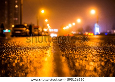 Foggy night in the big city, the headlights of the approaching cars on the road. Close up view from the level of the dividing line