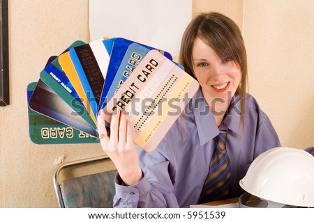 Young woman holding credit cards. helmet on table