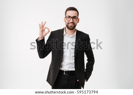 Image of attractive happy young bearded businessman wearing glasses standing and posing over white background make okay gesture.