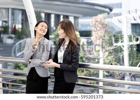 two asian woman stick closely together, two business girl smile & feel happy. 