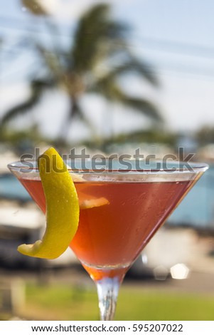 Tropical Red Martini Cocktail with a Slice of Lemon and Palm Tree Backgroun
