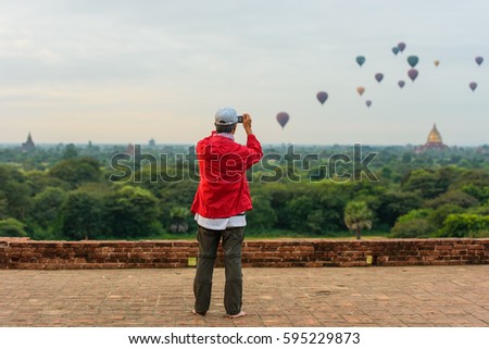  Man take picture hot air balloons over historic buddhist temples and stupas, Bagan, Myanmar