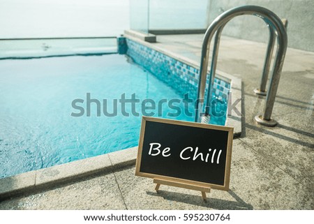 Blackboard with text be chill and swimming pool as a background.