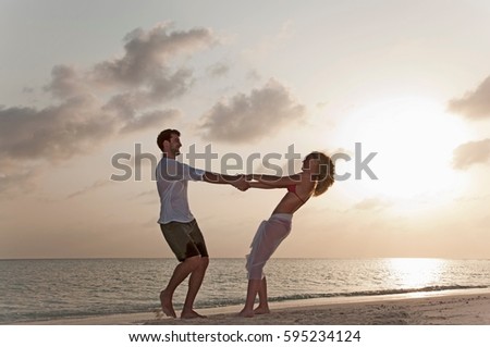 Couple playing on beach at sunset