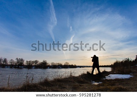 Professional photographer taking a photo flooding river at sunset 