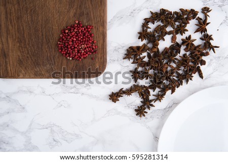 Close up portrait of anise seeds and spicy red pepper on wooden cutting board on white marble background