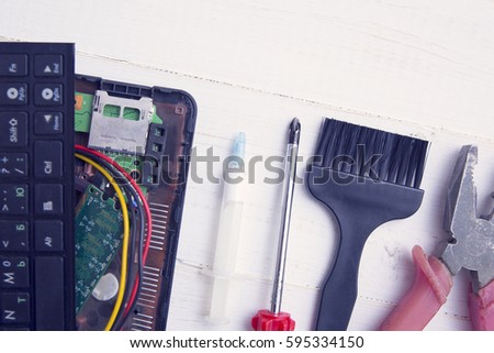 Broken laptop, screwdriver, pliers and brush for cleaning