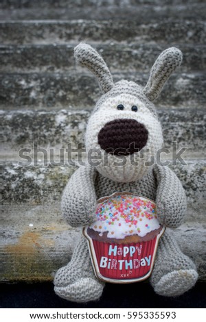 Cute dog toy with a cake in the legs. Congratulations with birth day