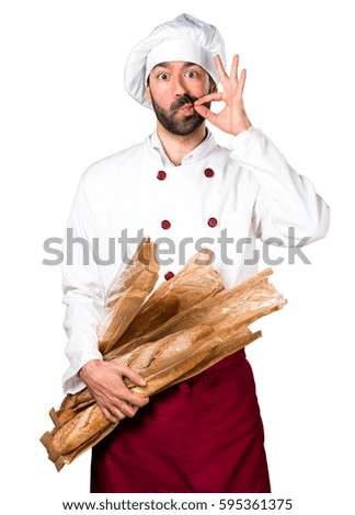 Young baker holding some bread and making silence gesture