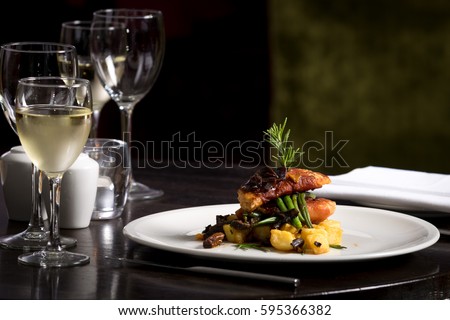 Restaurant table set  main dish steak fish cuisine fine dinning white wine glass cooler  candle light wooden table atmosphere menu Royalty-Free Stock Photo #595366382