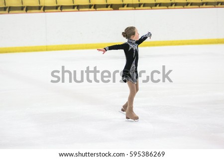 Little girl figure skating at the indoor ice arena.