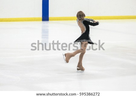 Little girl figure skating at the indoor ice arena.
