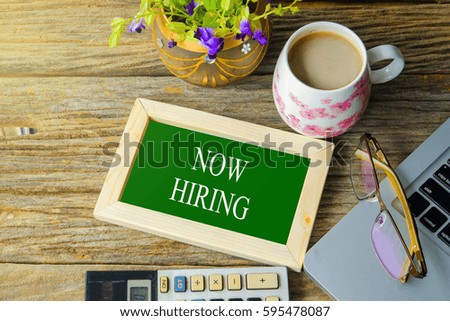Laptop , flower, calculator, glasses and mug with text NOW HIRING
