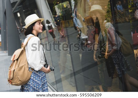 Woman shopping in Hong Kong Central. Young lady looking at shop windows holding camera. Urban mixed race Asian Chinese woman shopper smiling happy living in city.