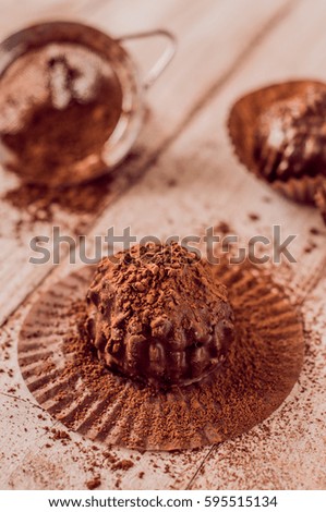 Chocolate chip muffin in brown wax paper. Unwrapped. Cocoa powder in the background.
